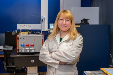 A researcher poses in front of high-tech machines.