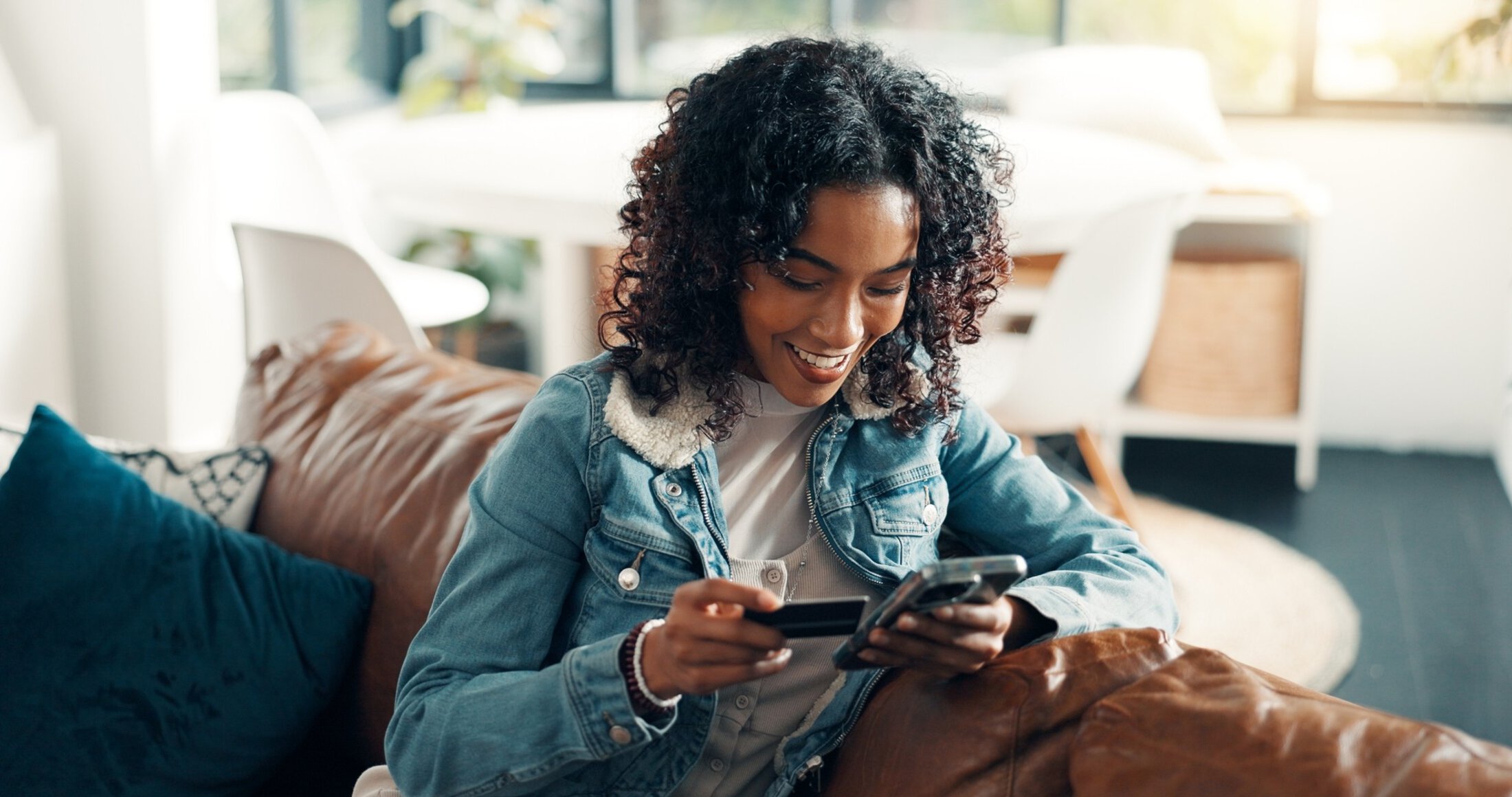 Credit card, phone and smile with woman on sofa for online shopping, ecommerce and sales discount. Digital payment, banking app and customer or person in living room of home for fintech and purchase