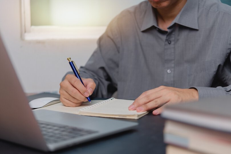 man hands with pen writing on notebook in the office.learning, education and work.writes goals, plans, make to do and wish list on desk..