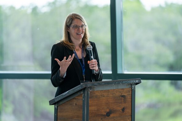 A woman at a podium gestures with her hand while speaking.