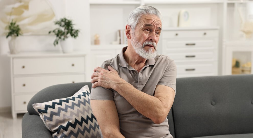 Arthritis symptoms. Man suffering from pain in shoulder at home
