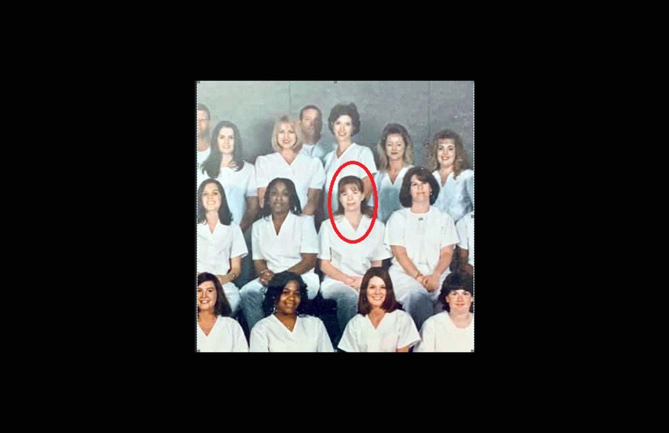 Group of women wearing nursing uniforms. There is a red circle around the woman who's center right. She has brown hair with bangs.