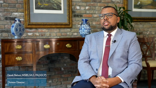 A man in professional attire sits for an interview.