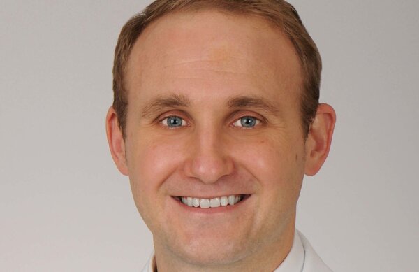 Headshot of man with light colored hair. He's smiling.