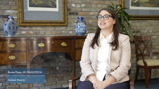 A woman in professional clothing sits and speaks to the camera for a video interview.