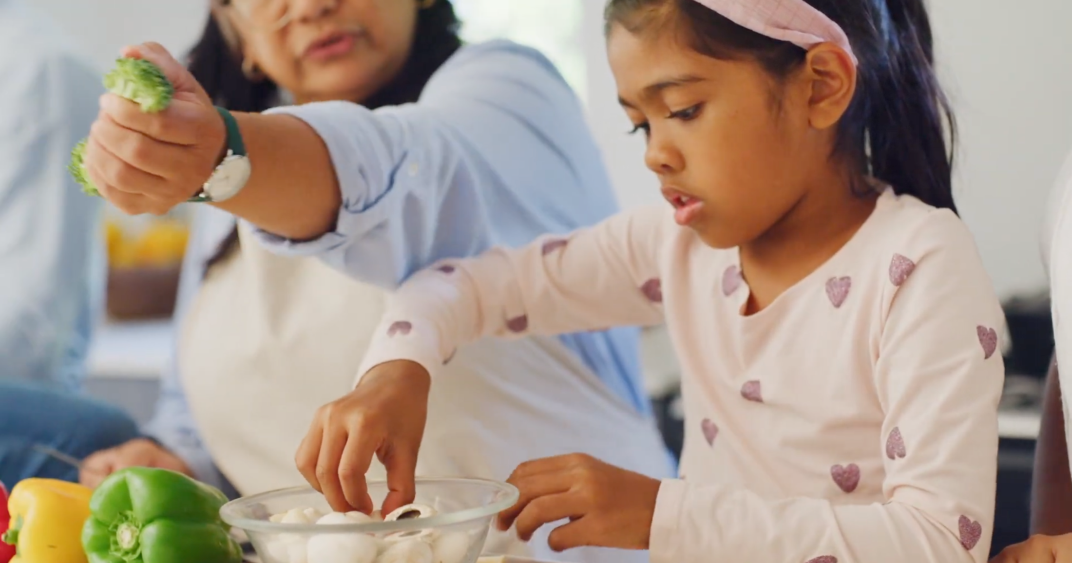 A culturally diverse mother and daughter prepare vegetables to eat during their healthy meals