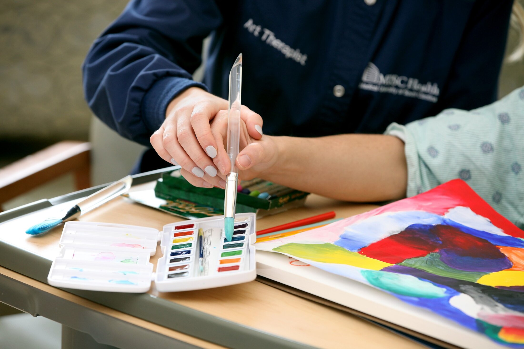 MUSC Senior Creative Arts Therapist, Marie Doll, helps a patient paint while he her room as therapy..Art in Healing Program..Art and Music..