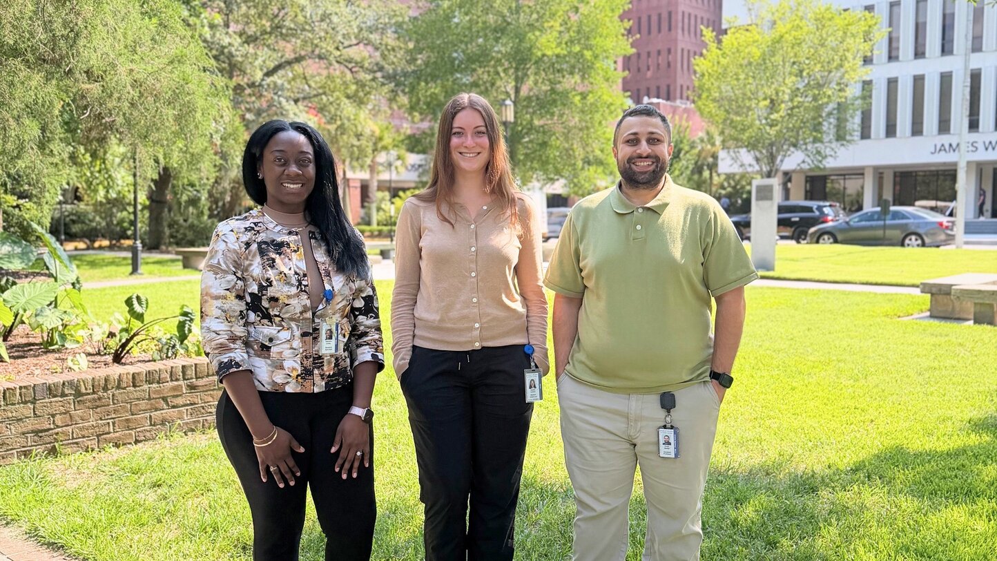 Tialeisha Corley, Sophia Leclerc, and Khalil Mallah, Ph.D., stand together on the lawn in front of MUSC.
