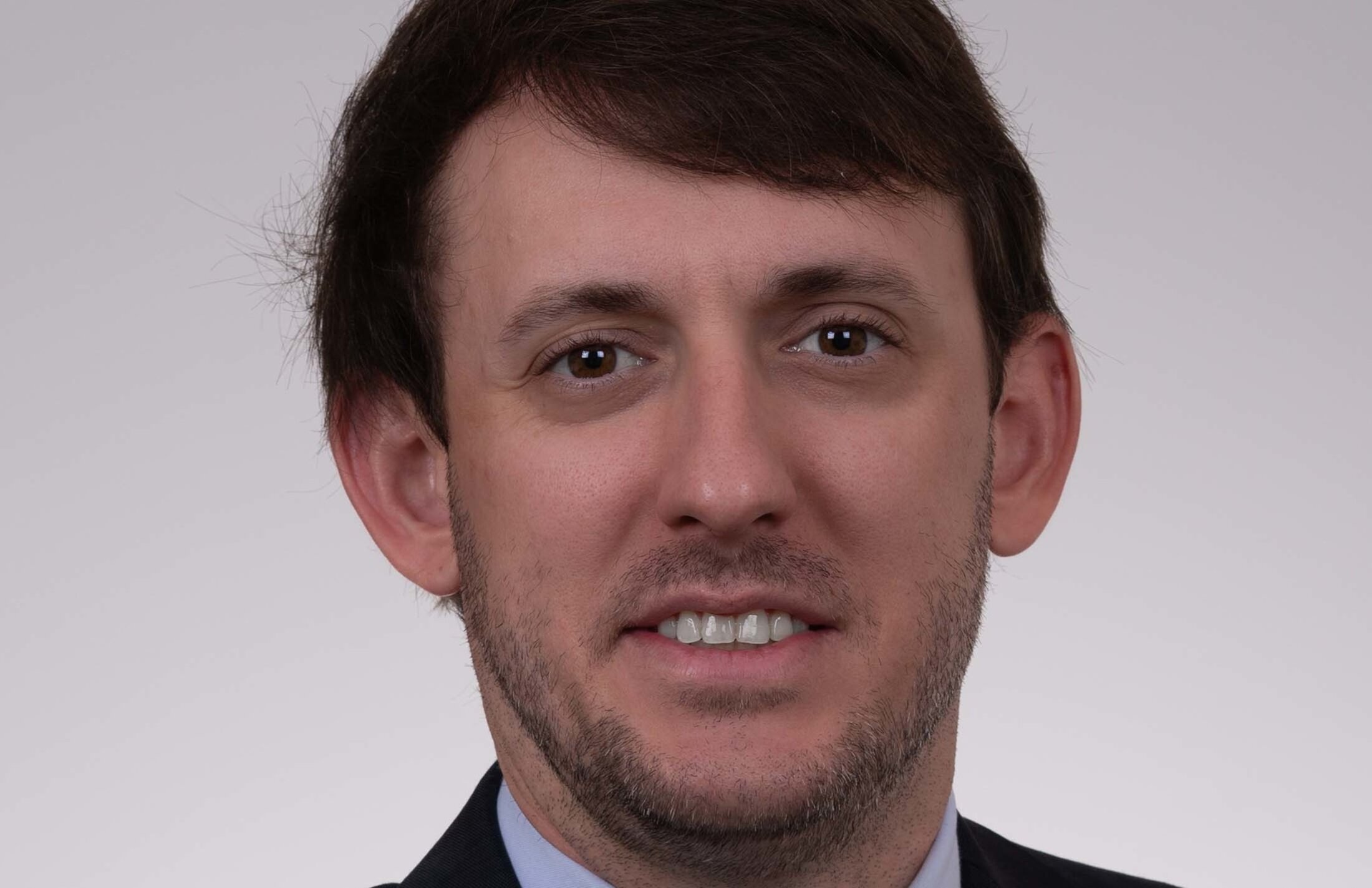 Headshot of man with brown hair and a faint beard.