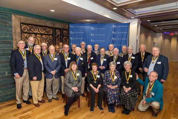 A diverse group of older people wearing gold medallions posing for a photograph, showcasing their camaraderie.