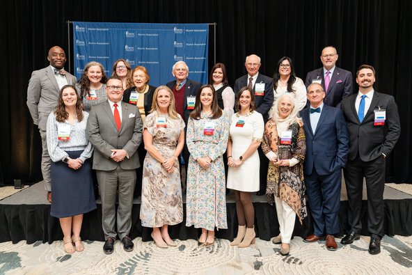 A diverse group of people standing together on stage, smiling