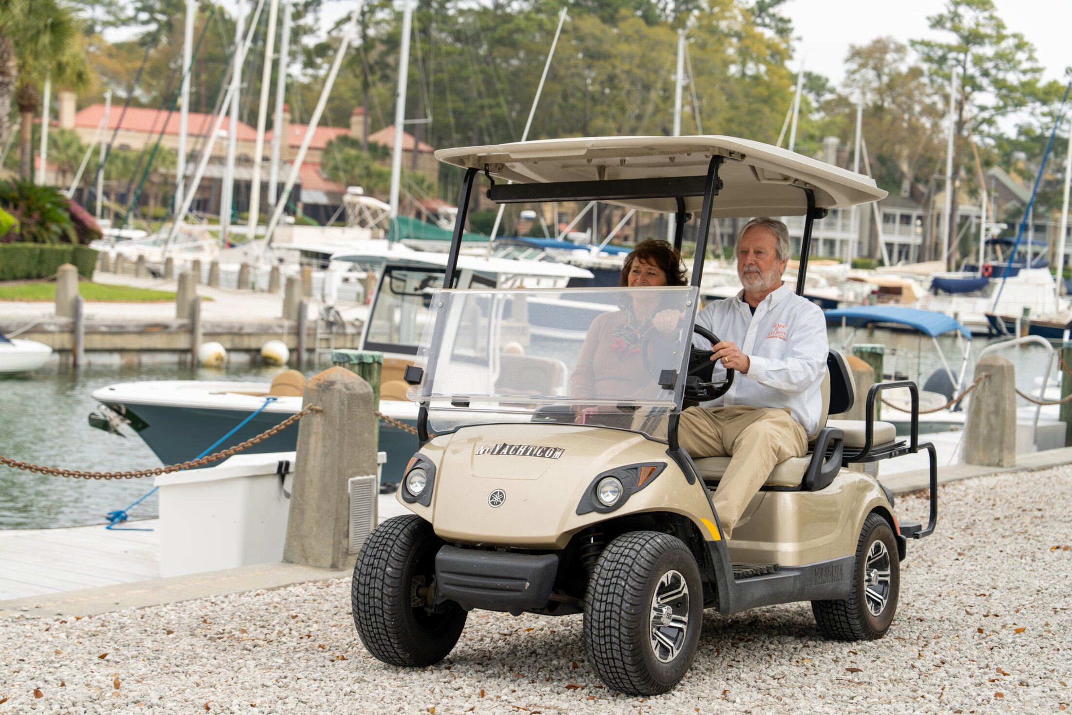 Billy and Linda Douglas zip past a marina in their golf cart.