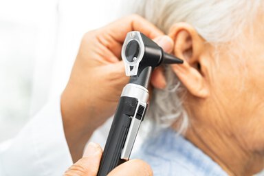 Close-up of a healthcare professional using an otoscope to examine an elderly patient’s ear during a routine ear check.