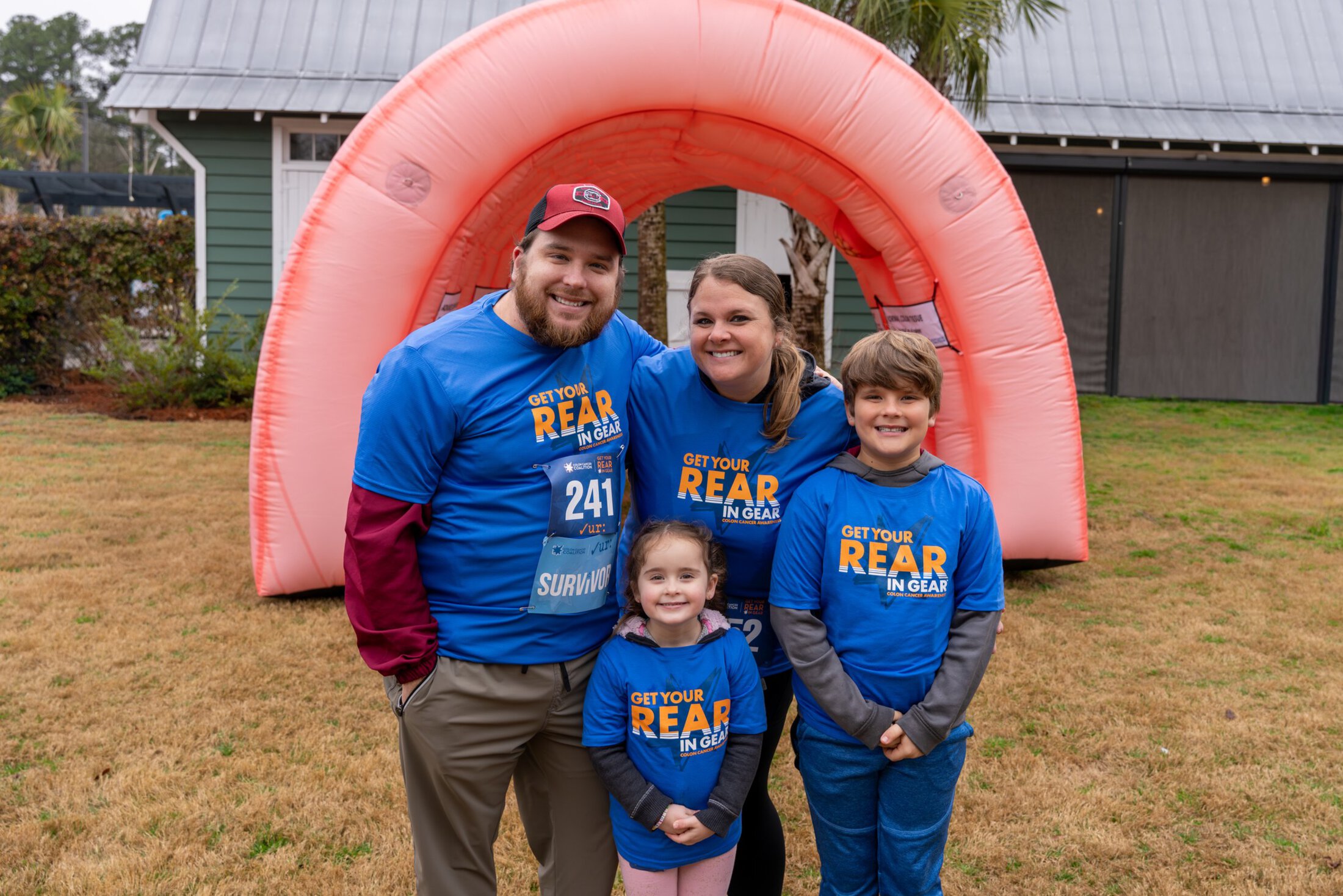 a smiling family poses at a community 5k to raise money and awareness for colorectal cancer