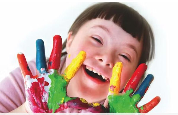 Smiling special needs child with paint on their hands.