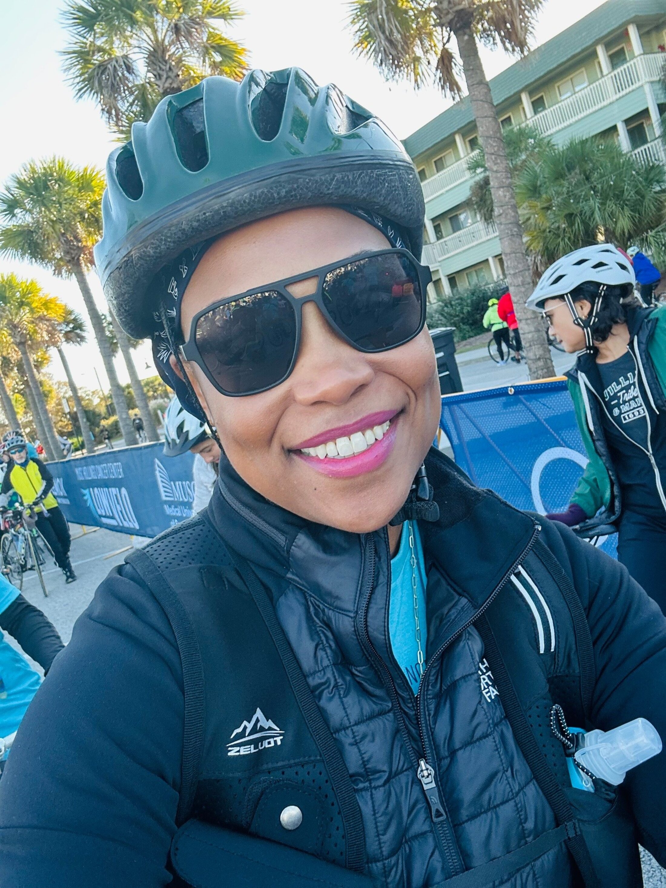 A woman in bike helmet and a warm puffy jacket takes a selfie.