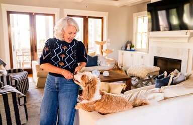 A woman plays with her dog in a comfortable living room.