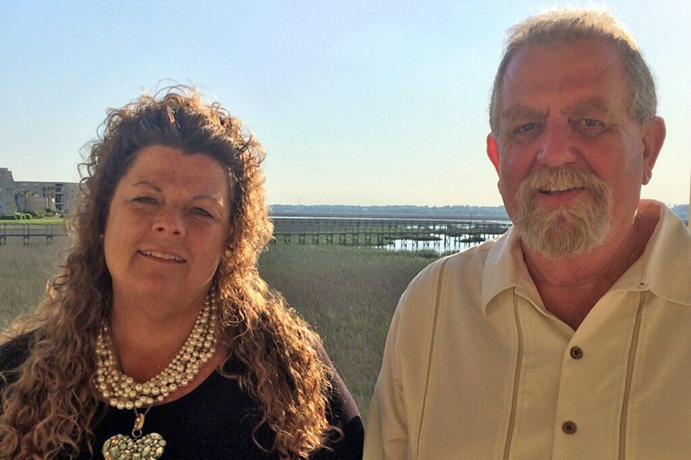 A couple pose in front of the marsh and docks.