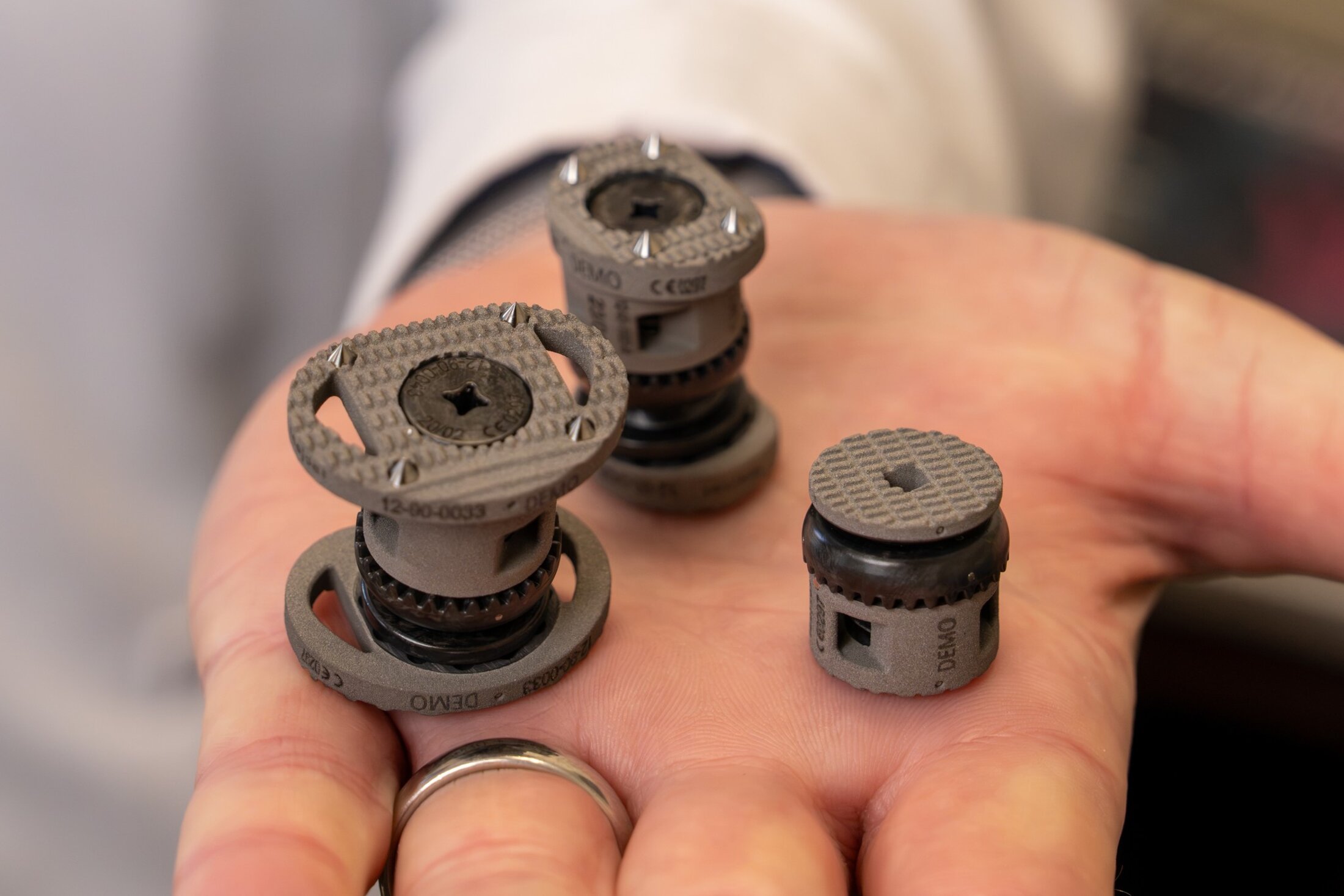 Closeup of three demonstration surgical implants in the palm of a physician's hand.