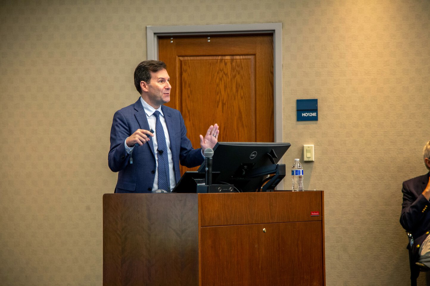 A man speaking at a podium gestures with his hands.