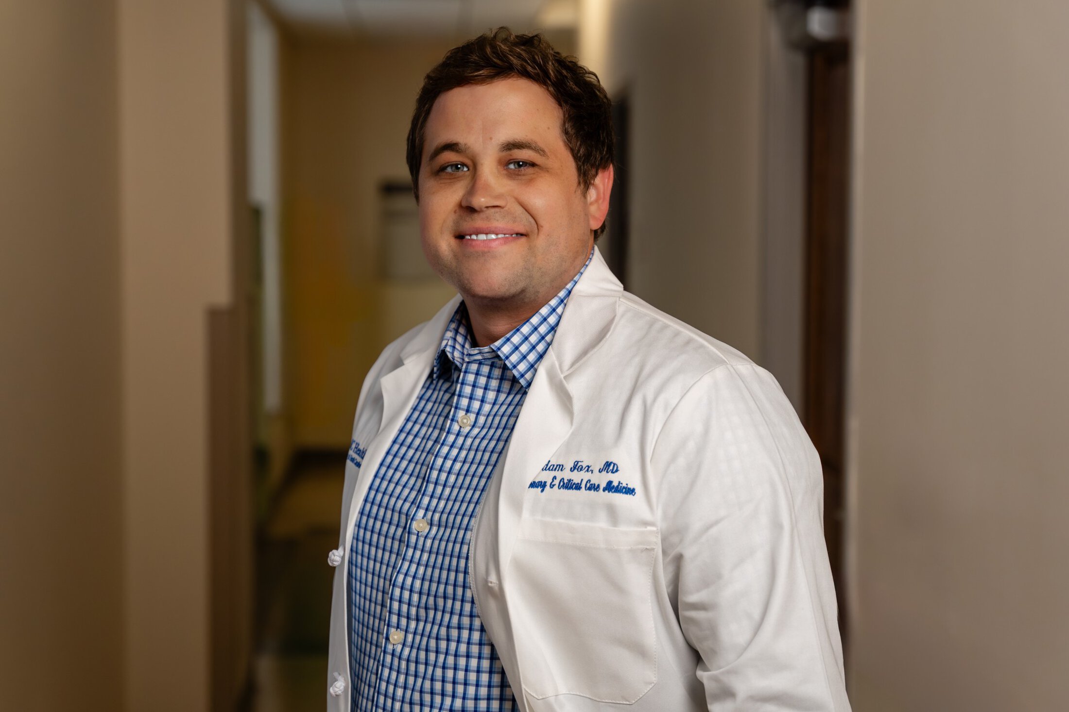 Adam Fox in a white doctor's coat in a clinic hallway