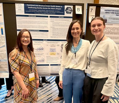 three women stand in front of a research poster