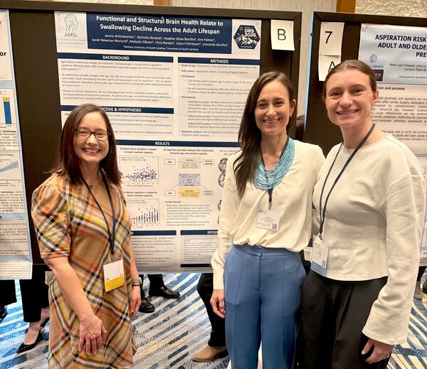three women stand in front of a research poster