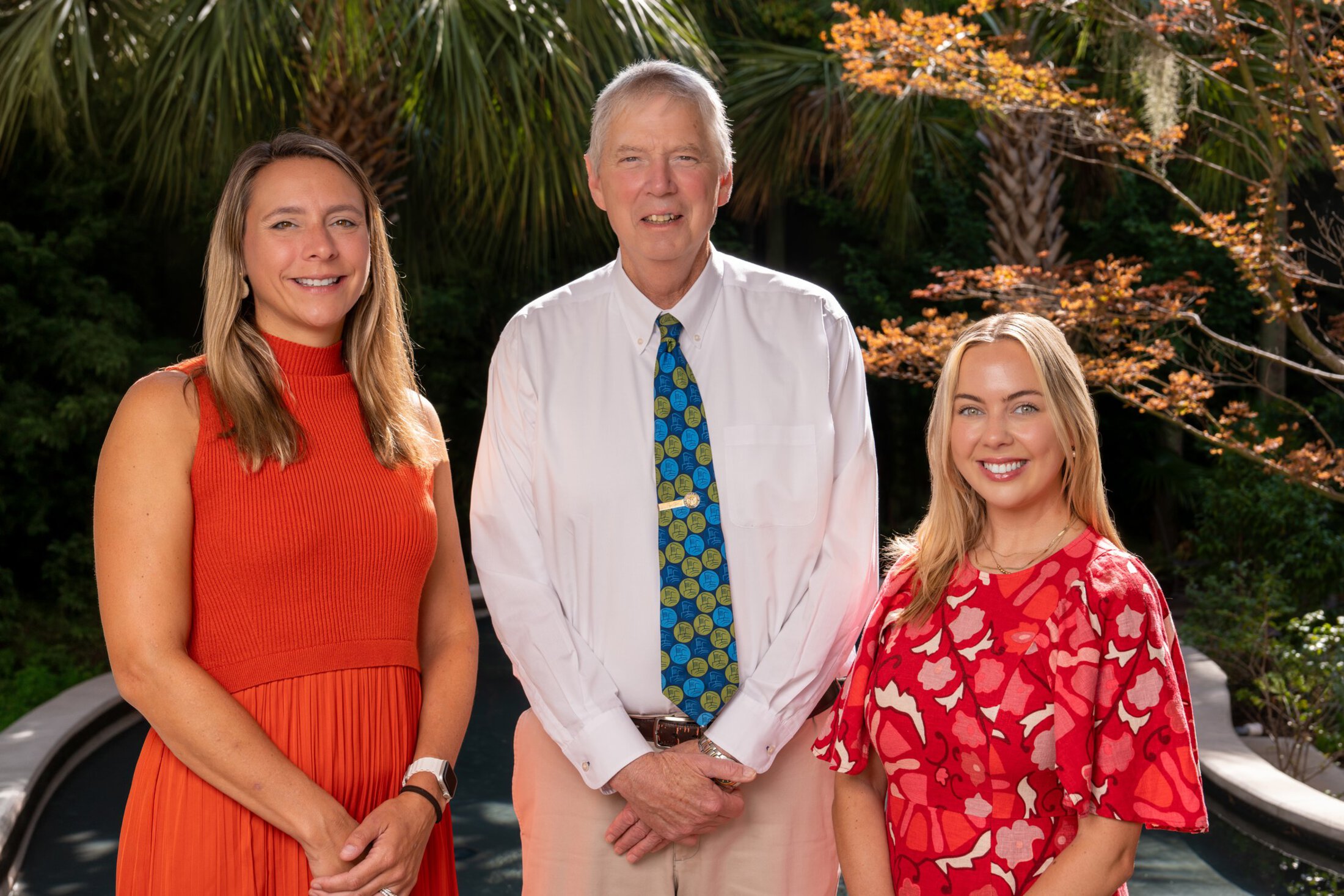 Three tobacco researchers pose together in a garden.