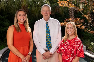 Three tobacco researchers pose together in a garden.