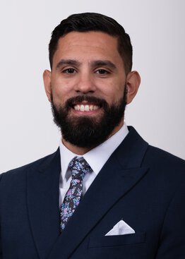 Ritchelli Quintao wearing a blue sport coat and dress shirt and tie