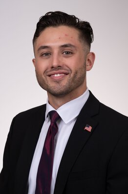 Coulter Small wearing a dark sport coat with dark red tie and pin
