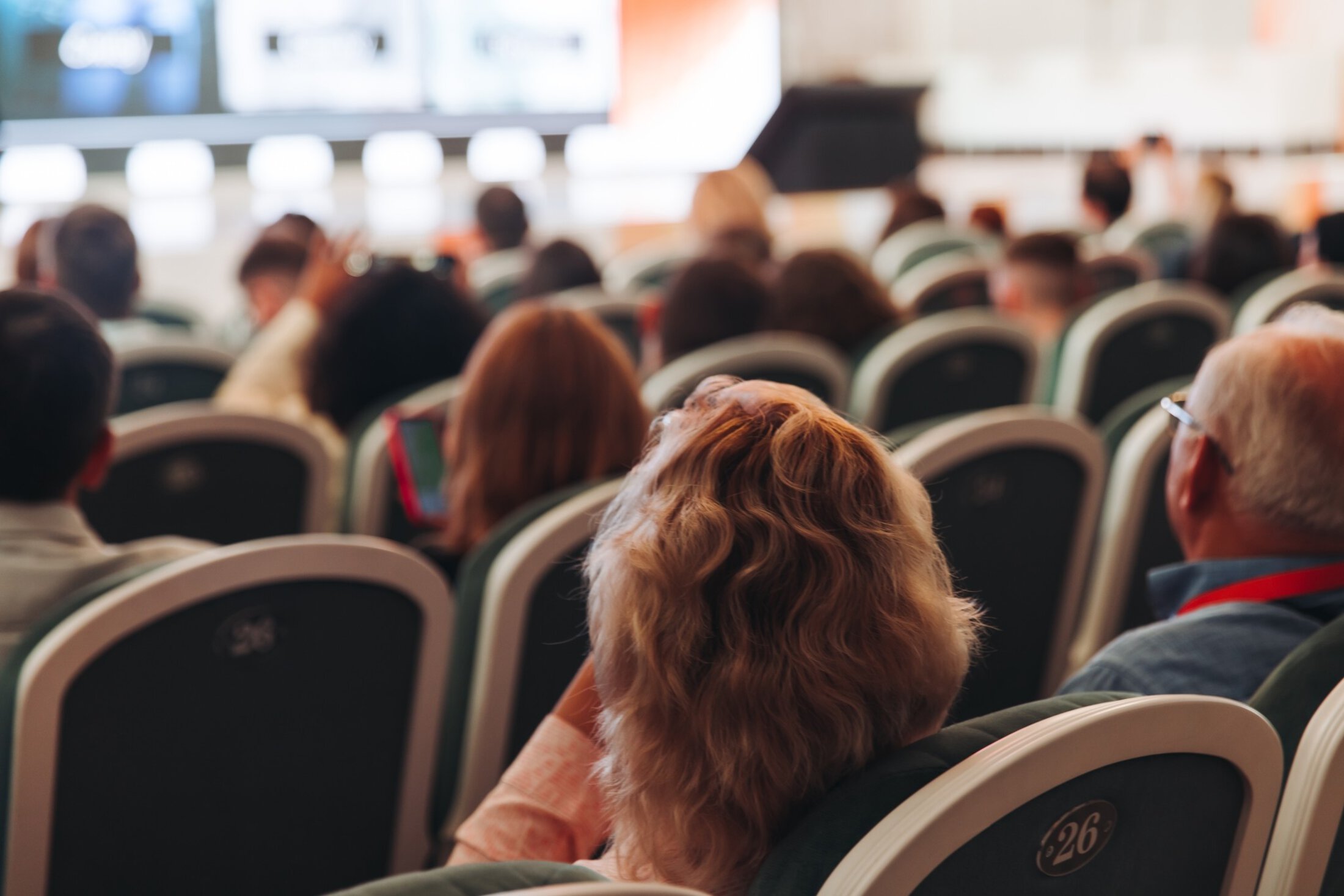 Audience at the modern conference hall listens to panel discussion, people on a congress event together listen to speaker on stage at convention, business seminar, large venue for forum presentation