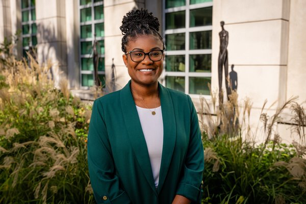 Dr. Amboree, standing outside of Hollings Cancer Center by statues and a garden.