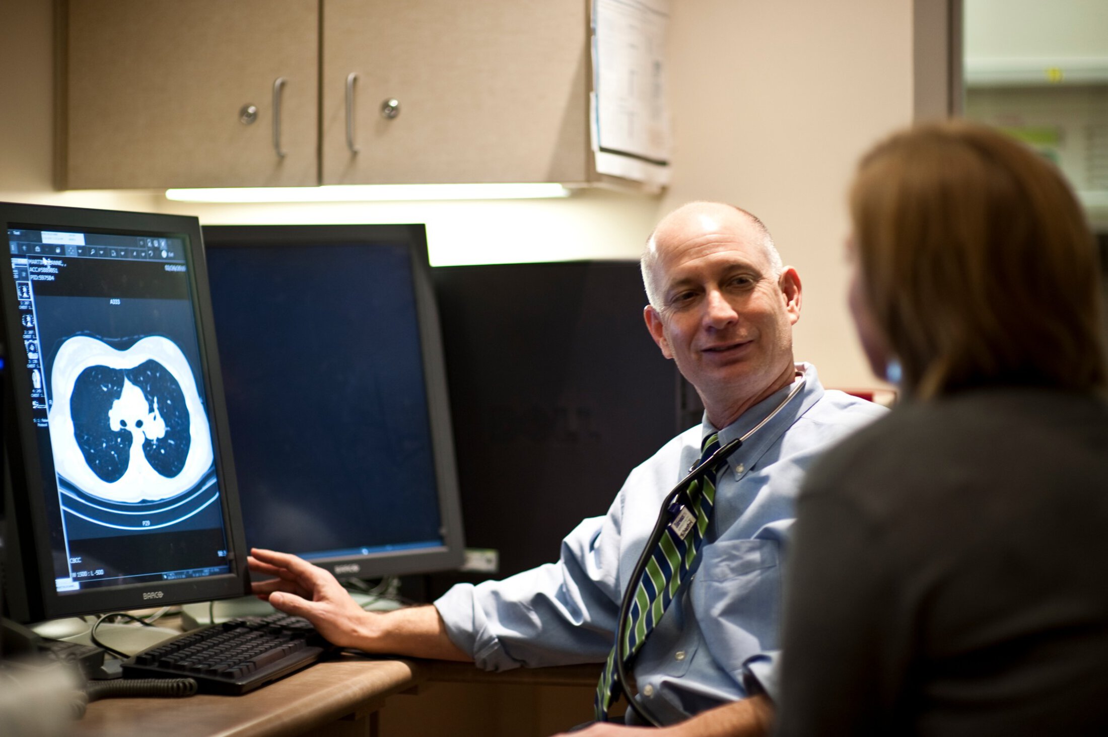 A doctor confers with a colleague while looking at a lung scan.