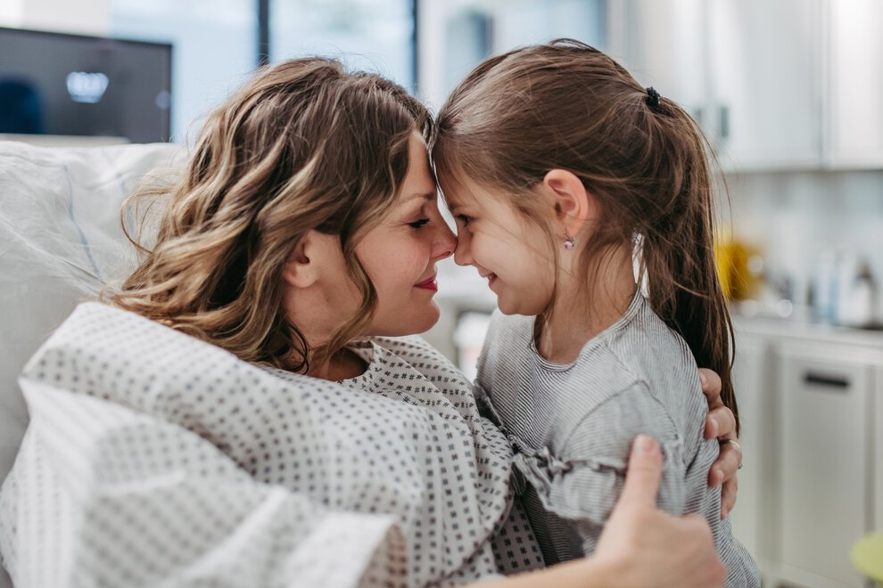 Daughter visiting mother in hospital after surgery. Emotional support from family for patients in hospital.