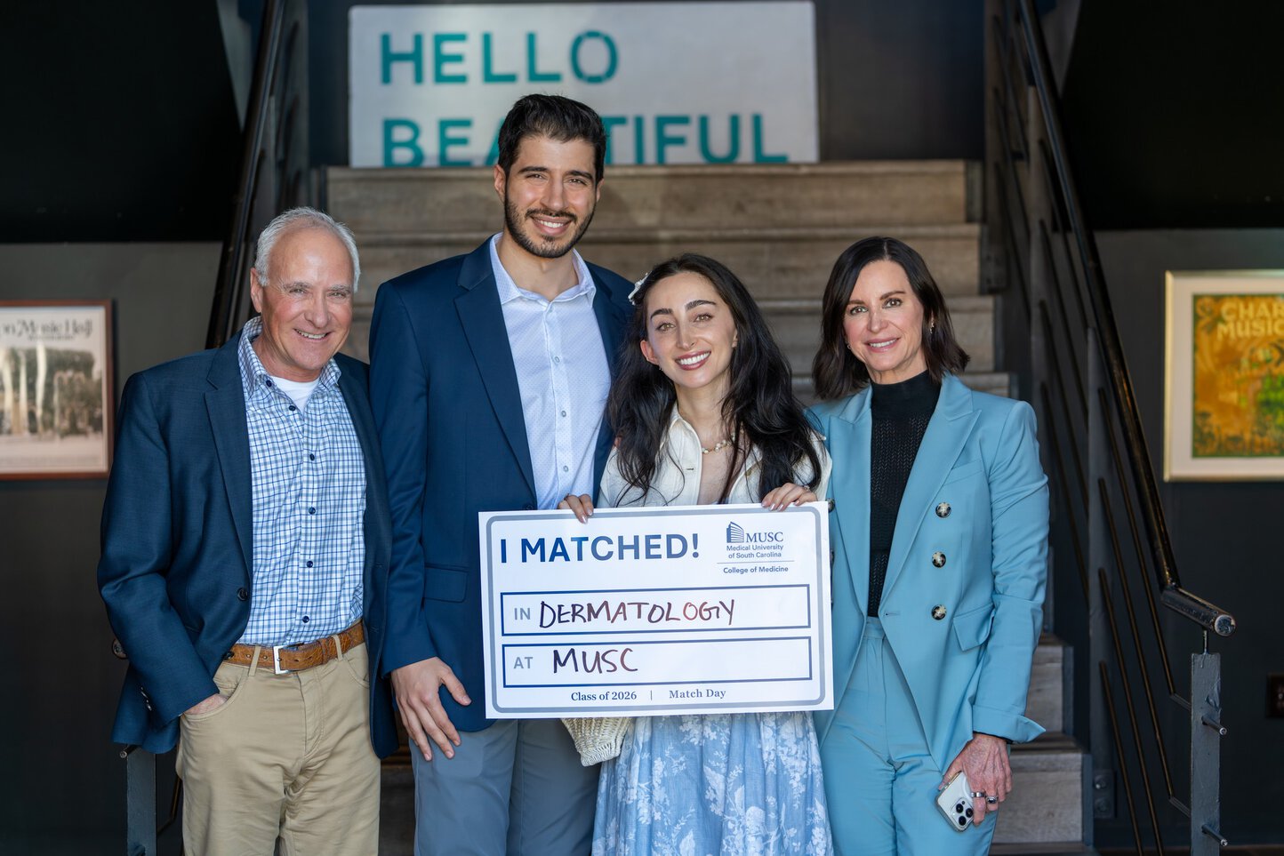 A young medical student, flanked by her parents and fiance, holds a sign that says I matched in dermatology at MUSC.