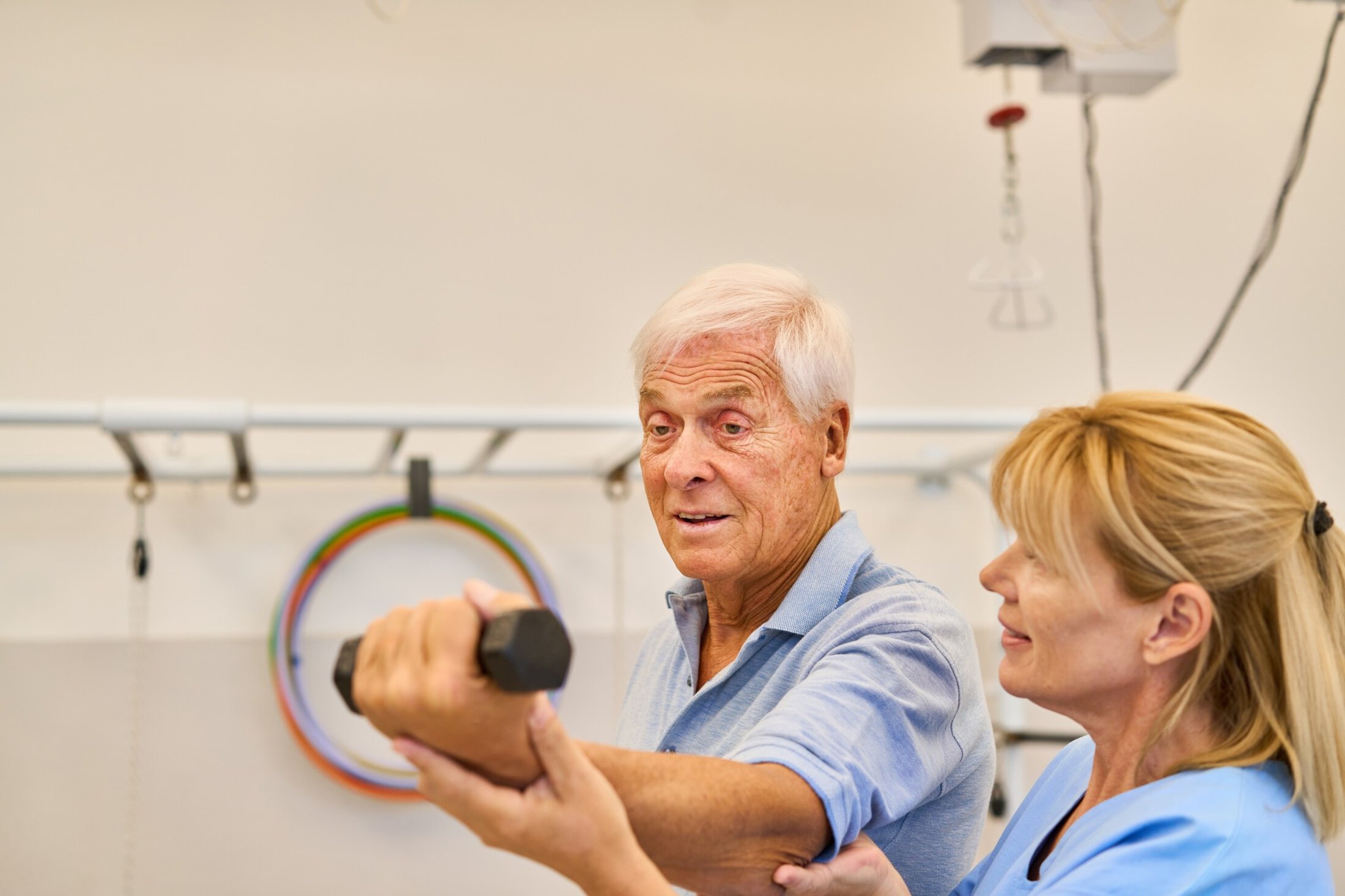 Elderly man participating in physical therapy with nurse assistance to improve mobility and strength. Rehabilitation therapy in a professional and supportive environment focuses on senior health.
