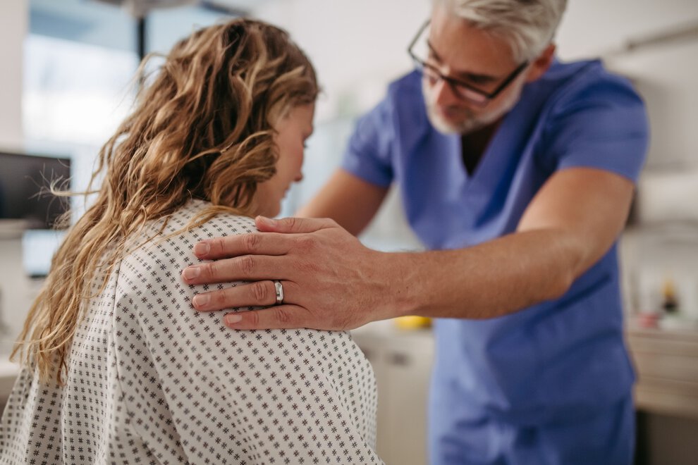 Doctor showing female patient MRI scan on tablet, discussing test result in emergency room.
