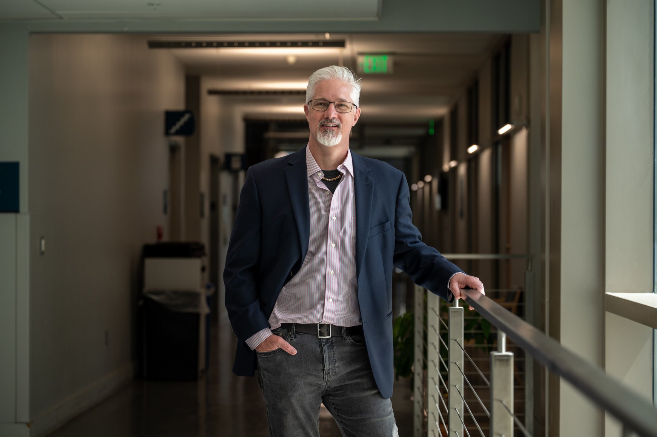 Doctor standing in hallway with hand on railing.