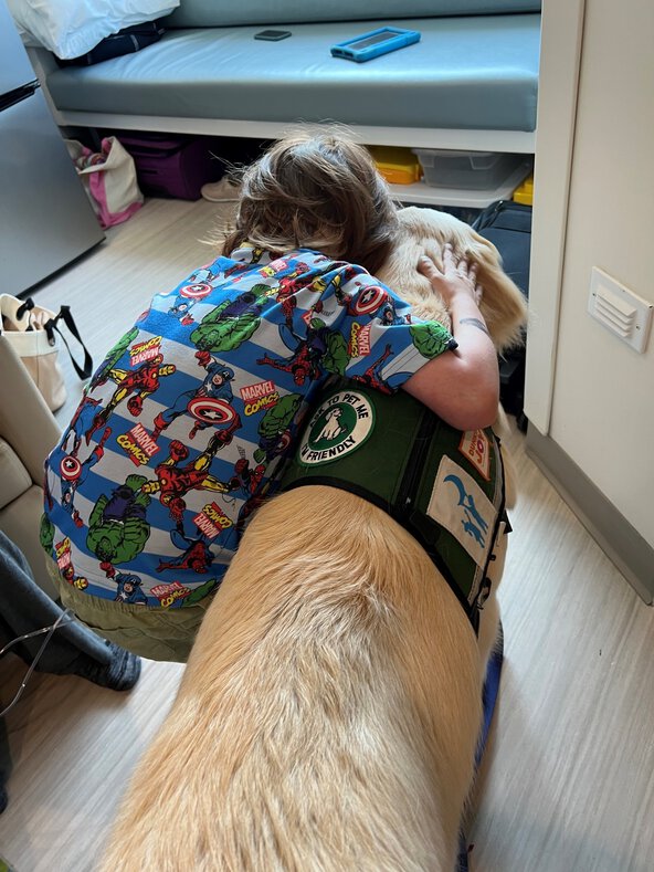 A child patient hugging therapy golden lab dog