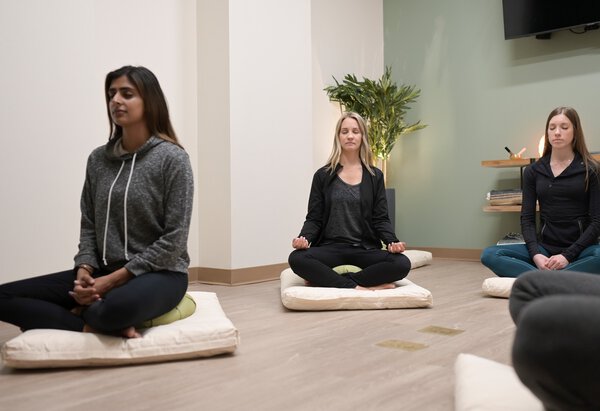 A room of patients practicing meditation all looking to reduce stress and anxiety through yogic breathing