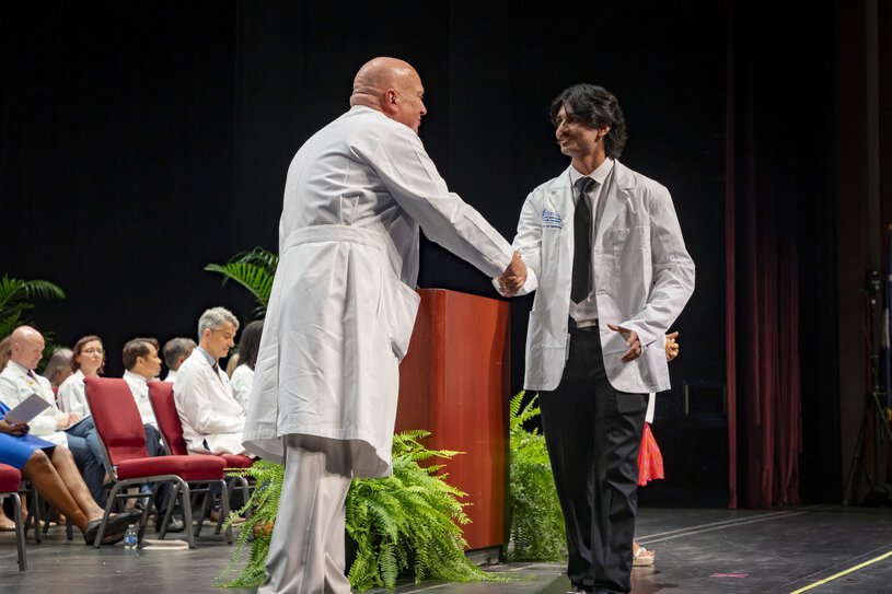 MUSC College of Medicine white coat receiving an award at the podium