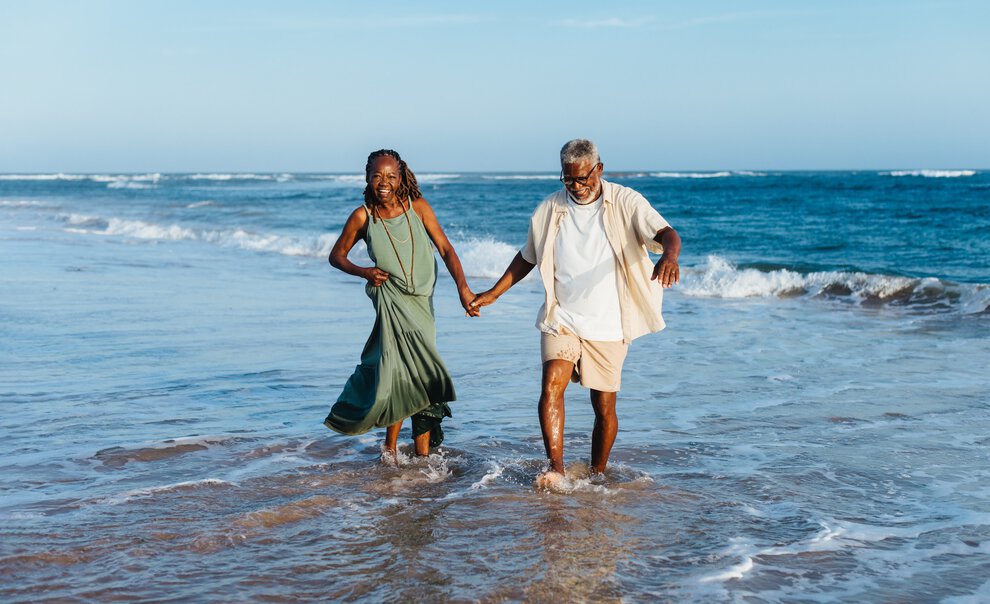 A couple wades in the ocean and laughs.