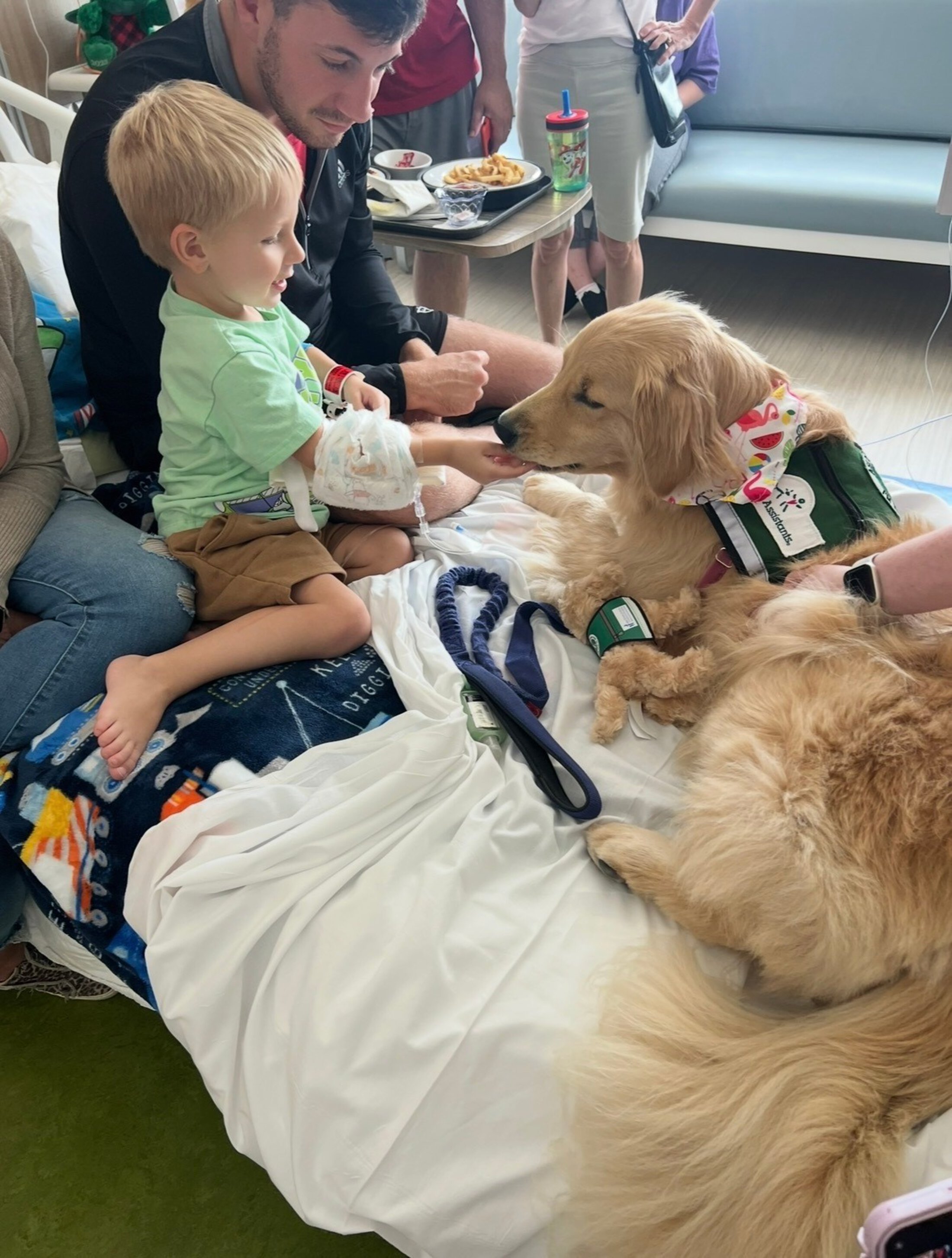 a pediatric cancer patient bonds with a therapy dog lying calmly on his bed at the children's hospital